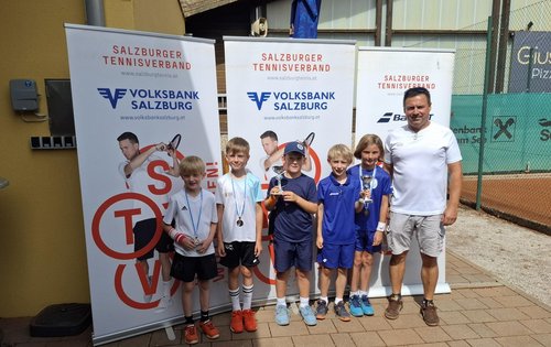 Tennis-Nachwuchs mit Pokalen vor Salzburger Tennisverband-Bannern in Salzburg
